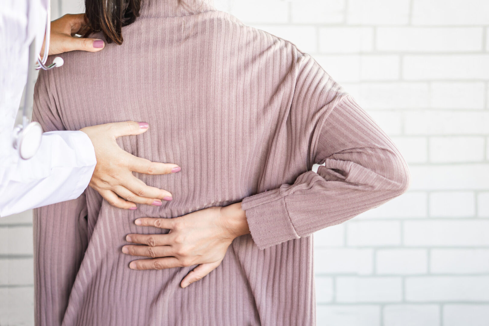 female doctor examining a patient suffering from lower back pain, healthcare and medical concept